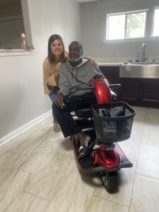 smiling man seated in mobility scooter moves back into his renovated home
