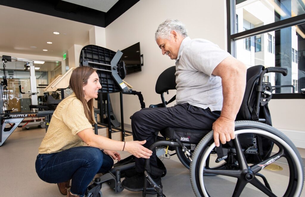 A caregiver assists an elderly man in a wheelchair
