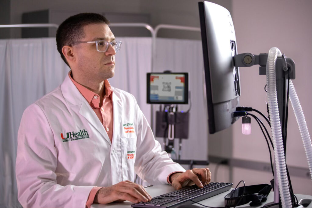 A researcher with spectacles and a white coat checks information on a computer screen at a desk