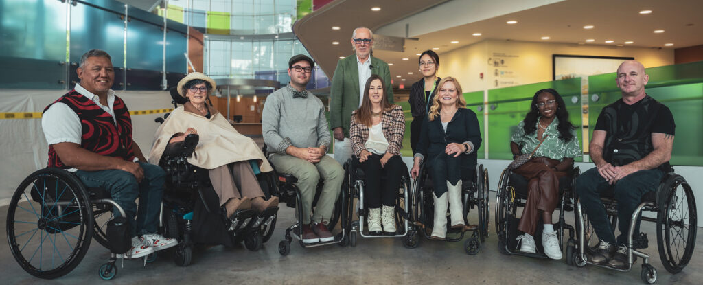 group of individuals in wheelchairs posing for group photo in lobby setting